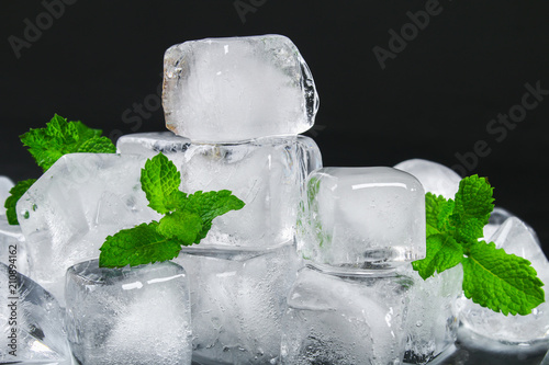 Cubes of ice from water with mint leaves on a black background.