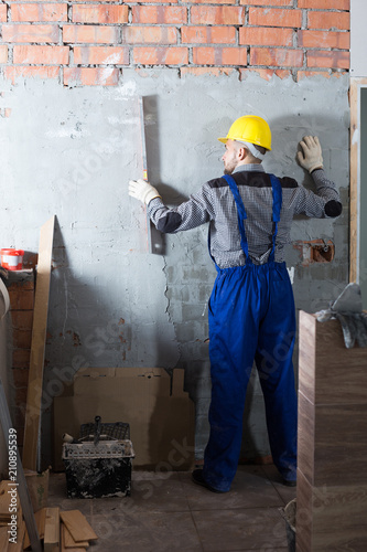 Man in helmet is measuring wall