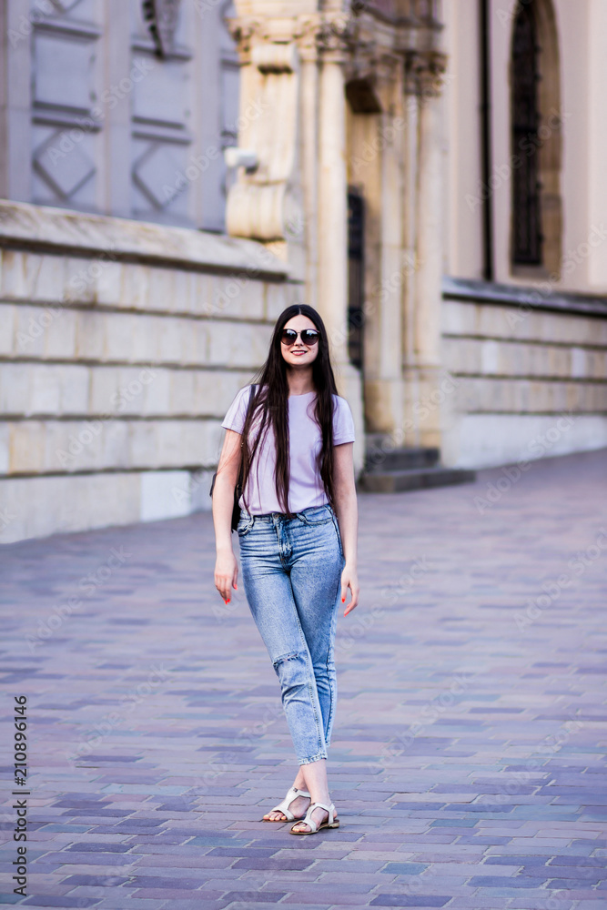 Young beautiful sexy girl in a T-shirt jeans and wearing glasses, walking  in the old