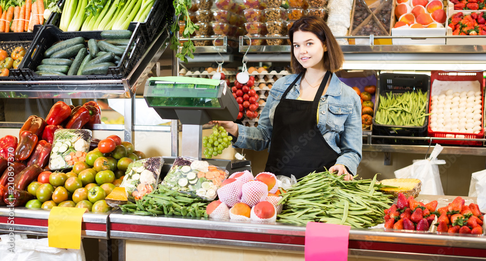 shopping assistant weighing fruit and vegetables in grocery shop