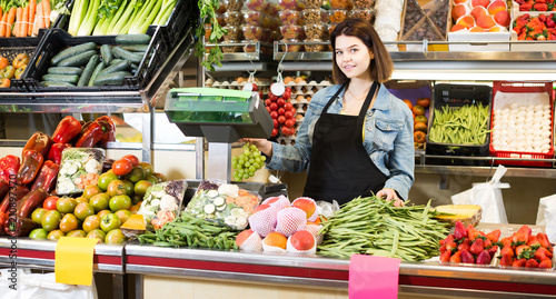 shopping assistant weighing fruit and vegetables in grocery shop