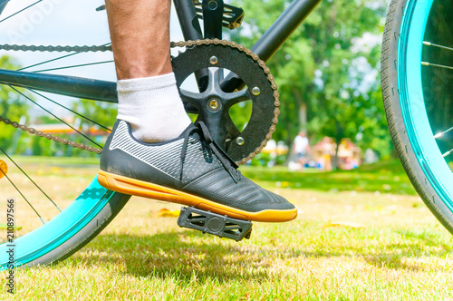 Cycler`s foot on pedal bicycle in a park at summer photo