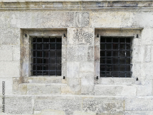 The windows in the concrete wall are covered with bars.