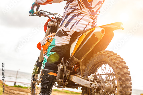 man riding a motocross in a protective suit in the mud