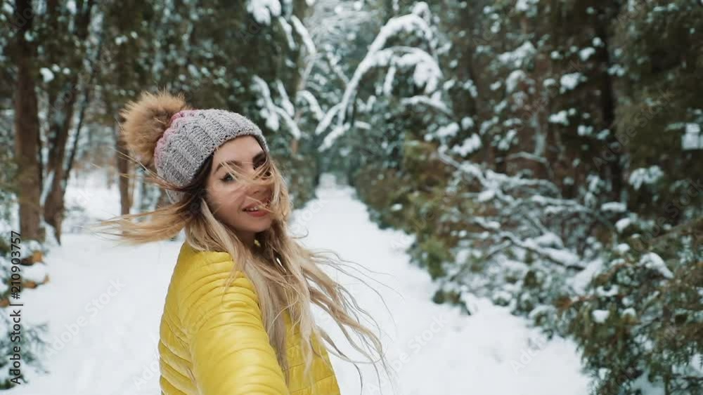 Follow me in the snow forest, happy girl .Young woman leading a man forward to the adventure Follow me in the snow forest, happy girl .Young woman leading a man forward to the adventure
