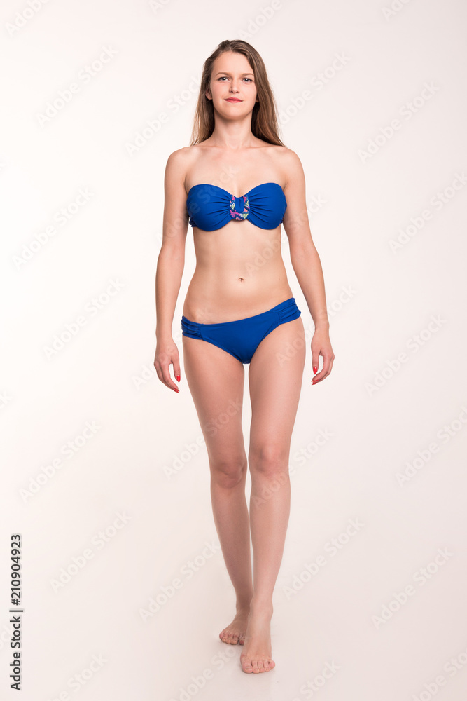 A girl in a blue swimsuit on a light background
