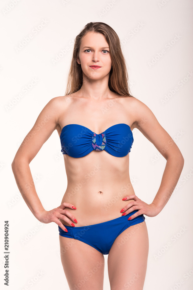 A girl in a blue swimsuit on a light background A girl in a blue swimsuit on a light background