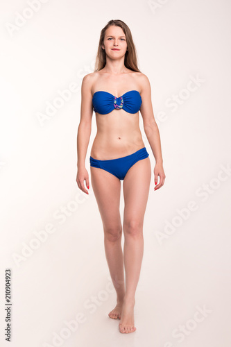 A girl in a blue swimsuit on a light background
