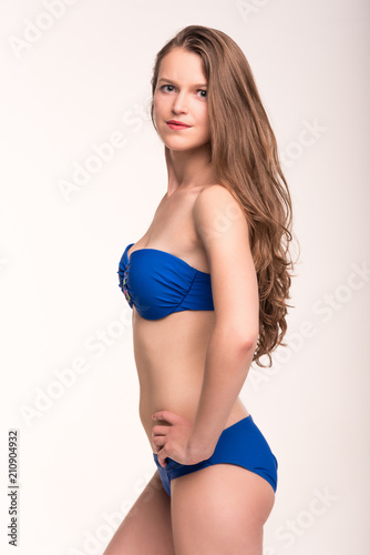 A girl in a blue swimsuit on a light background
