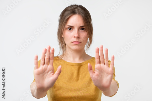 Young woman showing stop sign moving her hand palm to camera. Concept of negative emotion
