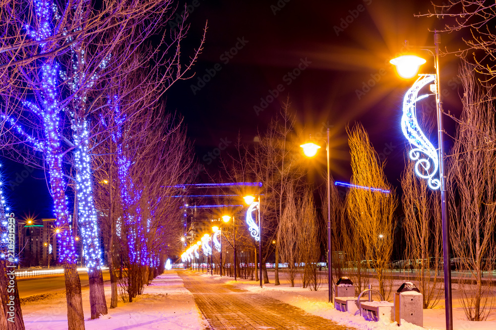 A colorful alley with trees decorated with garlands, New Year holidays

