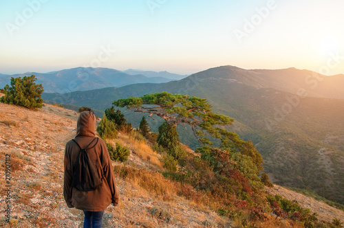 tourist with a backpack is at dawn on the mountainous terrain concept of travel