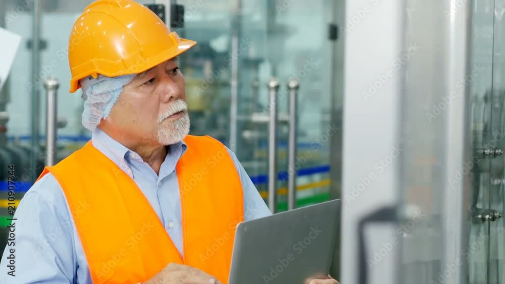 Senior engineer using laptop for work at production line.