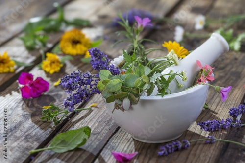 wild flower and herb leaf in mortar on a old wooden table background with flower on the table