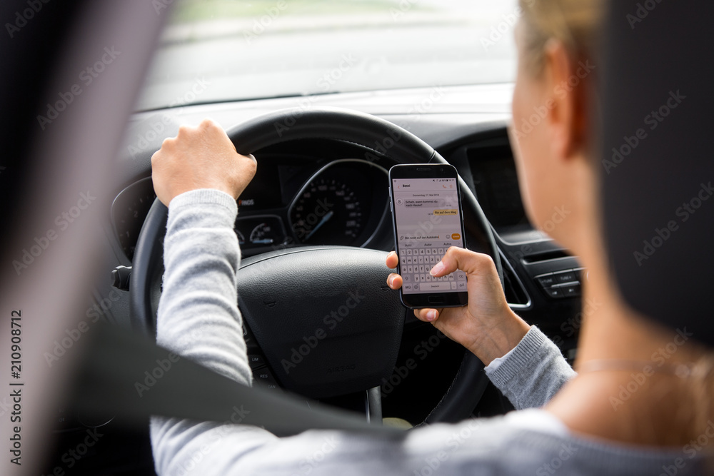 Junge Frau schreibt während der Autofahrt eine SMS Junge Frau schreibt während der Autofahrt eine SMS