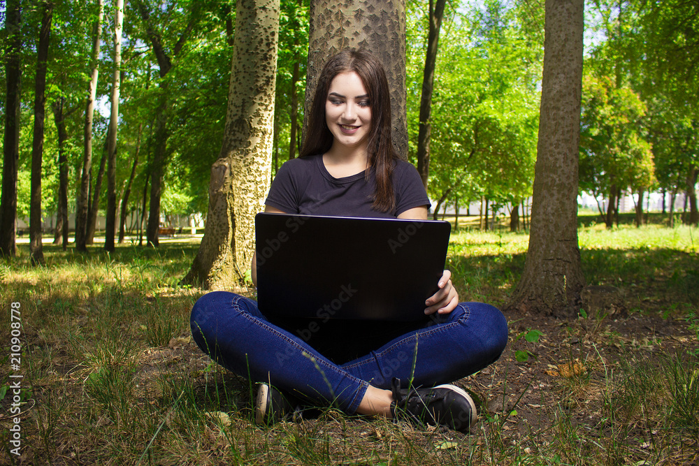 girl with a laptop sitting near a tree. girl with a laptop sitting near a tree.