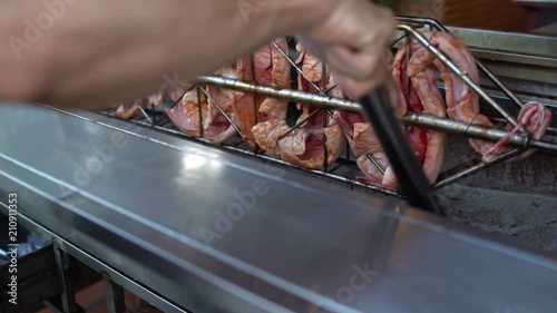 On a spit barbecue fried snake. Men's hand sneaks a forceps coals in a Brazier