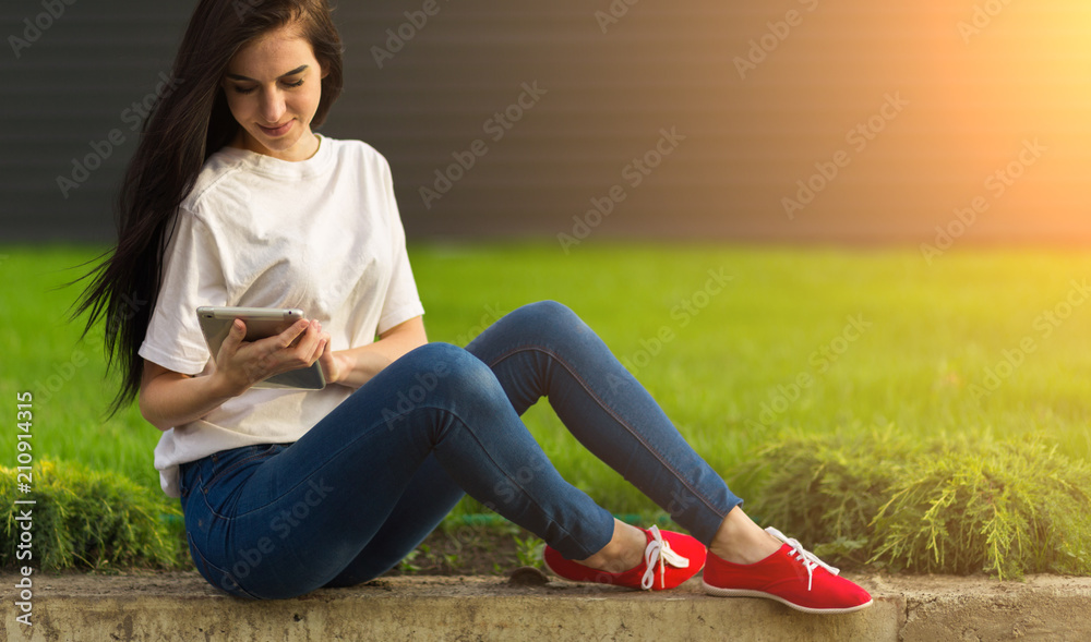 young brunette womanwith tablet serfing in internet on grass young brunette womanwith tablet serfing in internet on grass