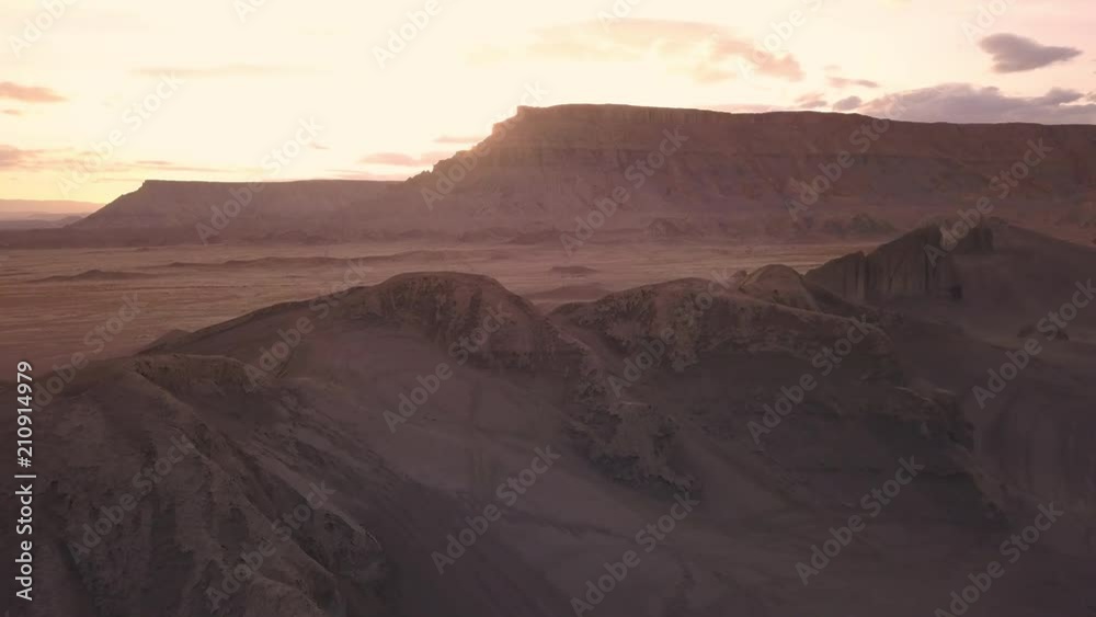 Flying over dunes at sunset with people on motorcylces in the distance at Swing Arm City, Utah.