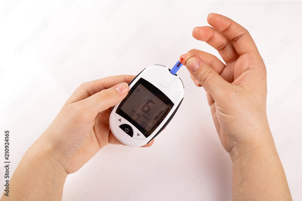 One person with diabetes doing a blood test with a glucometer isolated on white background One person with diabetes doing a blood test with a glucometer isolated on white background