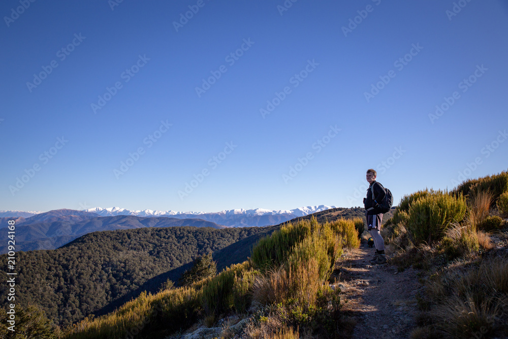 A man stops to enjoy the view from high on a mountain track