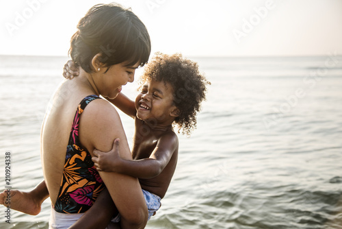 Mother carrying son at beach © Rawpixel.com