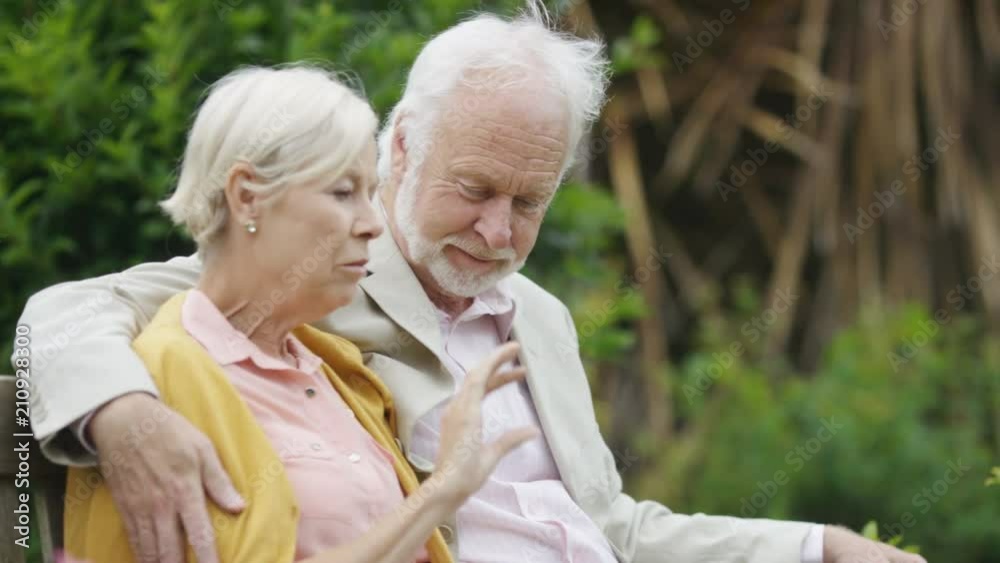 An older couple sat on a bench talking An older couple sat on a bench talking