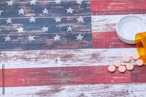 Bottle of pills spill on American flag with room for text photo