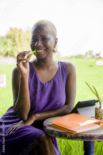 young attractive and happy black afro american woman working online with digital tablet pad outdoors on green grass field smiling cheerful