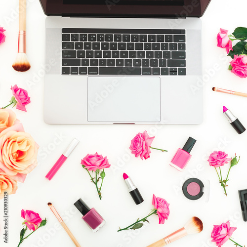 Laptop, roses flowers and cosmetics on white background. Flat lay. Top view. Feminine beauty composition