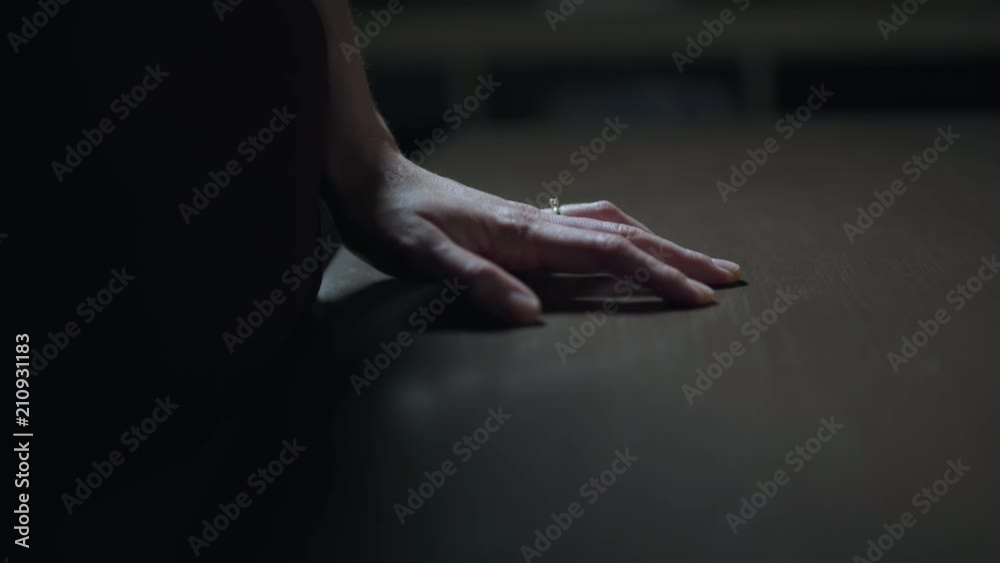 Woman rests her hand with engagement ring on a table