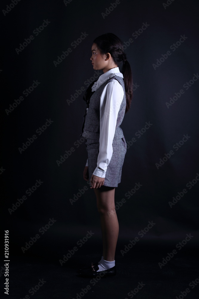 Business Kid Girl in formal suit stand on dark abstract background Business Kid Girl in formal suit stand on dark abstract background