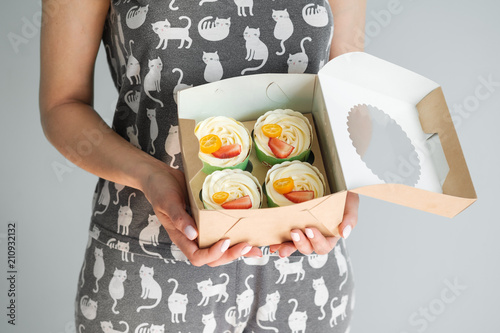 A bunch of cakes are in the hands of a woman. photo