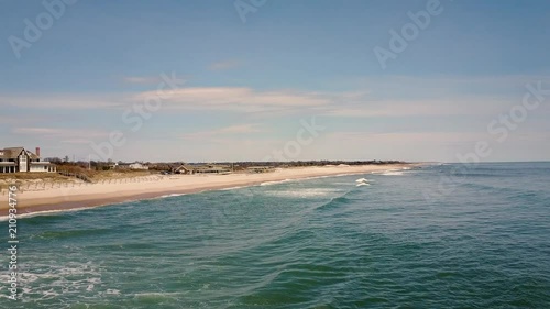 Aerial shot above the ocean closes in on boardwalk on East Hampton Main Beach photo