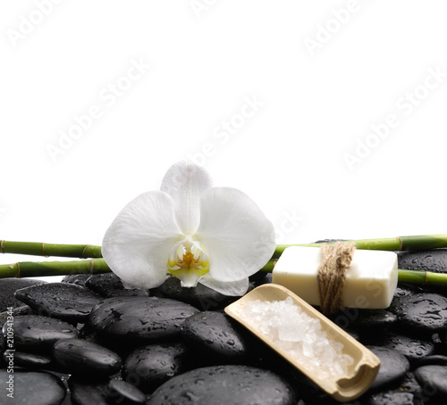 Pile of wet pebbles and orchid  soap  salt in bowl with long green bamboo