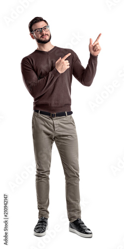 A bearded man in smart casual clothes looks in front to camera and points sideways with both hands and index fingers.