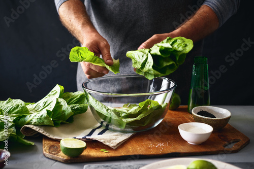 Quadro su tela Man preparing green salad romaine lettuce healthy food