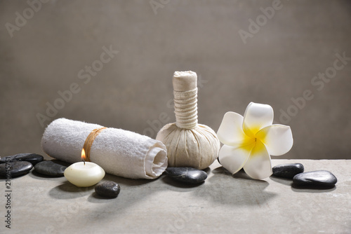 candle with pile of black stones and white frangipani  herbal ball.towel on gray background    