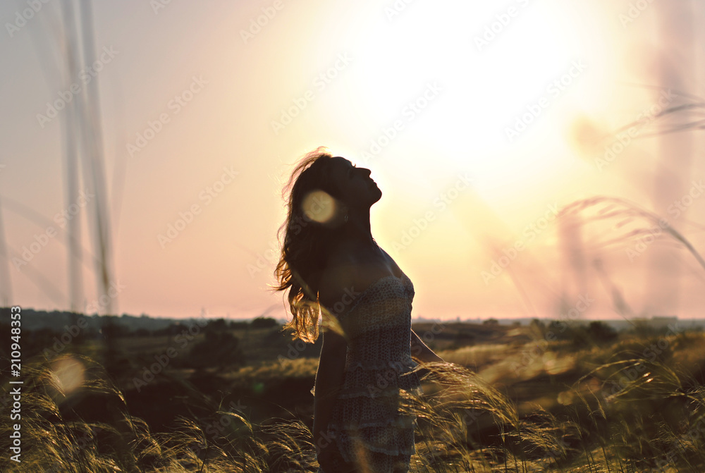 Fototapeta premium Silhouette of happy women in grass field at sunset. Summer happiness