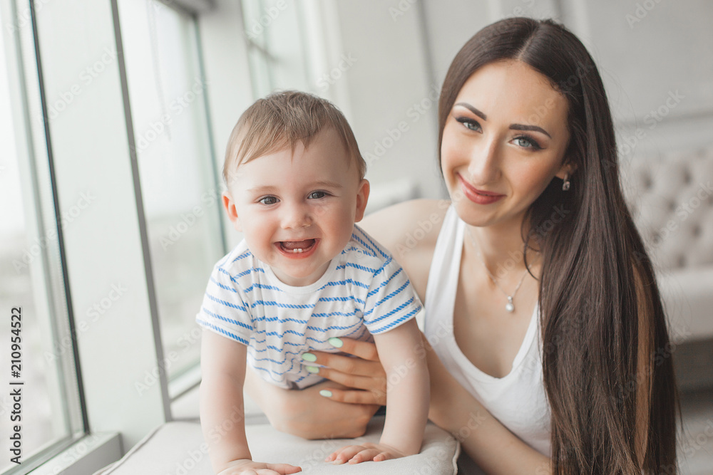 Young pretty mother playing with her little son. Cheerful family smiling at camera Young pretty mother playing with her little son. Cheerful family smiling at camera