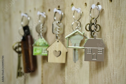 House key with wooden home keyring hanging on wood board background, property concept, copy space