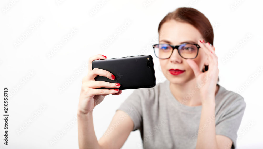 Portrait of a young attractive woman making selfie photo on smartphone isolated on a white background Portrait of a young attractive woman making selfie photo on smartphone isolated on a white background