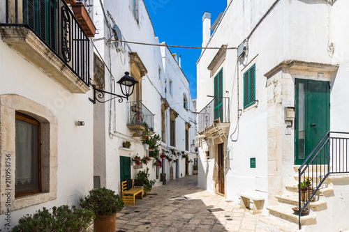 A street in Locorotondo with typical whitewashed houses and hanging flowers, Apulia, Italy