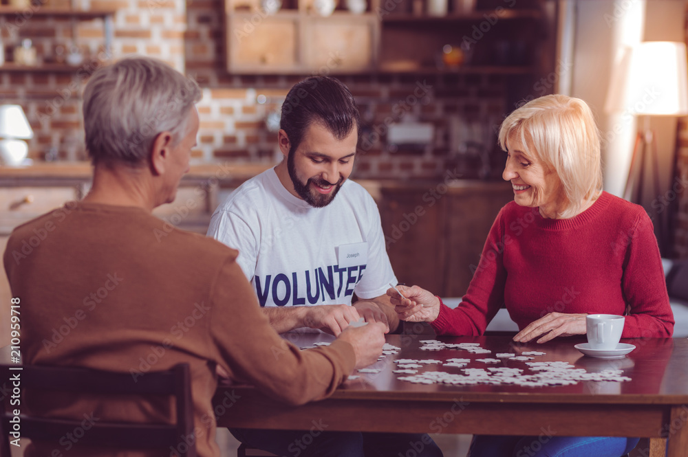 One team. Delighted mature woman keeping smile on her face while making picture with puzzles