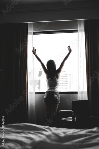 Asia woman get up on the morning and standing near the window.lady fresh and ready to go to work.silhouette and dark style. 