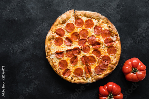 Pepperoni pizza on black concrete background. American pepperoni pizza, top view