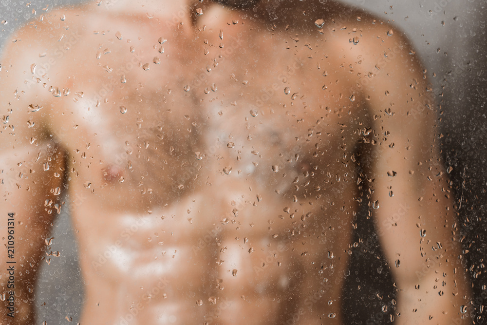 Blurred through glass view of man taking shower