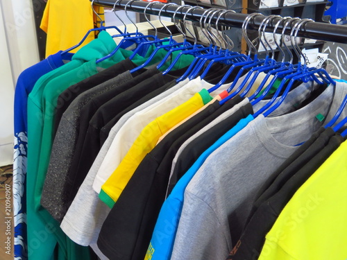 Clothes hanging on a hanger in the store. Choice of Women's t-shirts of different colors on metal hangers.