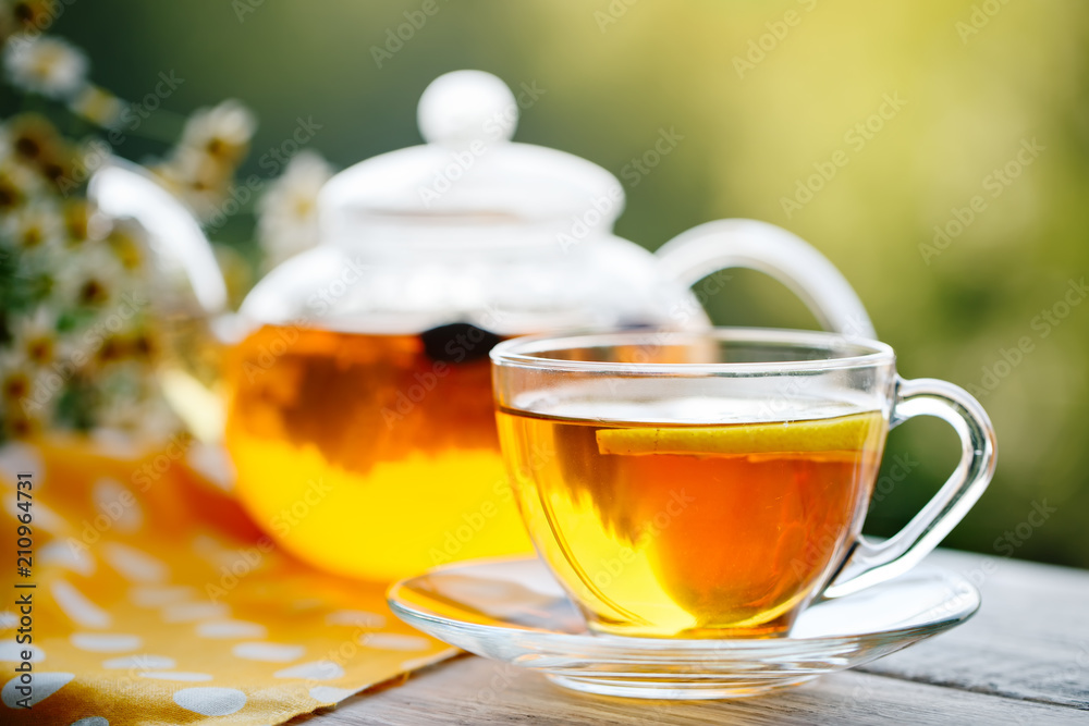 Cup with hot tea with mint and a thyme on a wooden table in a summer garden. Cup with hot tea with mint and a thyme on a wooden table in a summer garden.