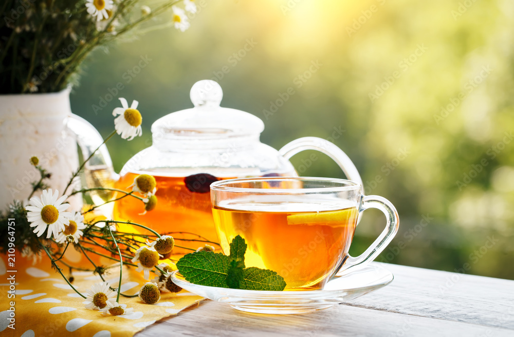 Cup with hot tea with mint and a thyme on a wooden table in a summer garden. Cup with hot tea with mint and a thyme on a wooden table in a summer garden.